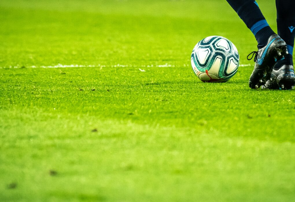 Una persona parada en un campo de fútbol con una pelota, representando a Lamine Yamal en 2025 Image source: https://unsplash.com/photos/man-playing-soccer-game-on-field-AWdCgDDedH0