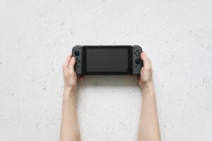 Una persona sostiene una consola Nintendo Switch 2 en sus manos sobre una mesa blanca Source: https://www.pexels.com/photo/hands-holding-nintendo-switch-near-white-surface-4523008/